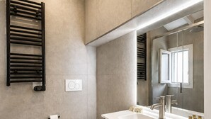 A modern bathroom with a bidet, toilet, and a large mirror.