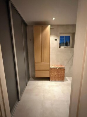 Un pasillo con un armario de madera, una pequeña cesta de mimbre y una ventana con vistas nocturnas.