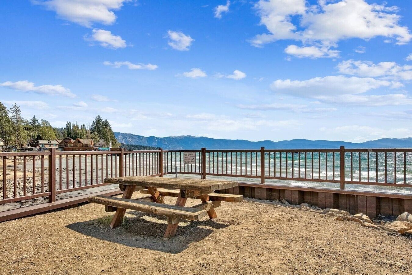 A picnic table with a metal railing and a view of the ocean.