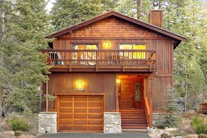 Eine zweistöckige Blockhütte mit Balkon, Garage und Stein Fundament.