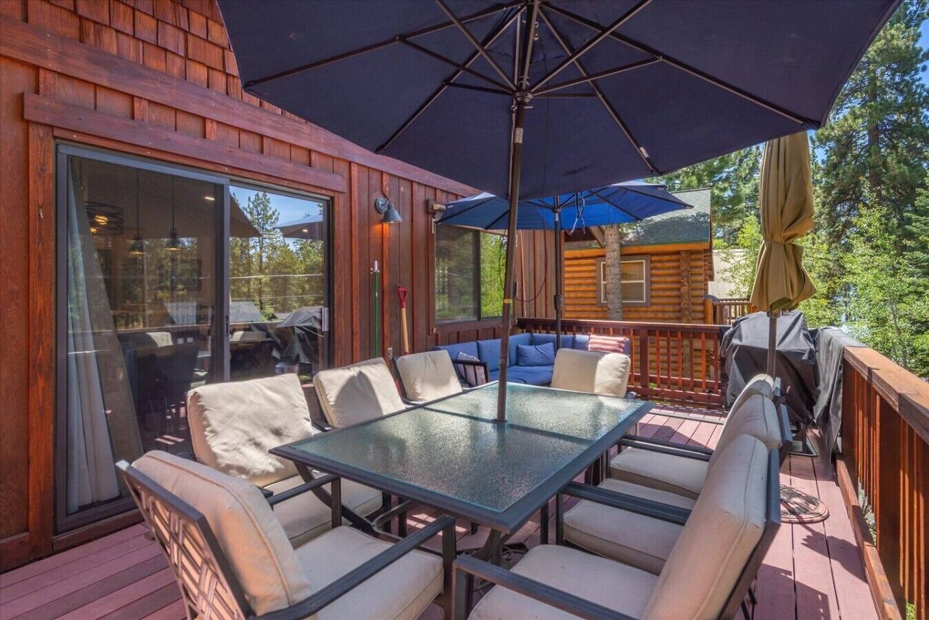 Una terraza con puerta de vidrio, una mesa con sillas y un paraguas grande.