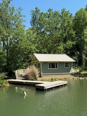 A lakeside cabin with a dock, surrounded by dense trees. - Cozy Cottage in the Mountains of Candler, 25 mins from Asheville (Candler)
