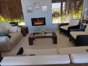 Un salon avec un téléviseur, des canapés, une table basse et une vue sur la verdure par la fenêtre.