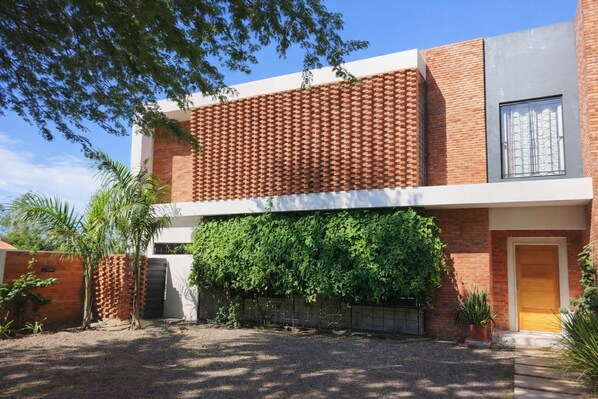 Un bâtiment moderne à deux étages, doté d’une façade en briques, d’une grande fenêtre à l’étage supérieur et d’une entrée abritée.