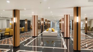 Eine geräumige Lobby mit einer zentralen Sitzecke, mehreren Säulen und einem spiegelnden Boden.