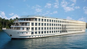 Ein großes Mehrdecks-Kreuzfahrtschiff mit zahlreichen Balkonen und Fenstern, das auf ruhigem Wasser schwimmt.