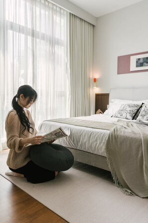 A person sitting on a yoga mat in a bedroom with a bed, curtains, and a wall-mounted light. - Chic Cityscape Stay in Bukit Bintang, TRX | 1-6pax (Kuala Lumpur)