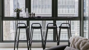 Ein modernes Zimmer mit großen Fenstern, einem Esstisch mit Stühlen und einer Couch.