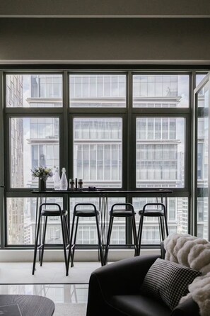 A modern room with large windows, a dining table with chairs, and a sofa. - Chic Cityscape Stay in Bukit Bintang, TRX | 1-6pax (Kuala Lumpur)