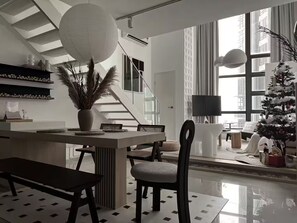 A modern living room with a dining area, a staircase, and a large window. - Comfy Loft in EkoCheras, Link to MRT | 1-6 pax (Kuala Lumpur)