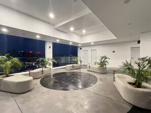 Een moderne binnenruimte met een ronde zithoek, grote ramen en potplanten.
