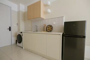 Une cuisine équipée d’un lave-linge, d’un réfrigérateur et d’un plan de travail agrémenté d’une assiette décorative.