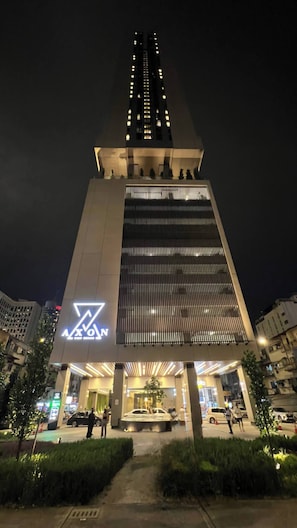 A modern building with a prominent logo at the entrance, a large vertical structure, and a well-lit facade. - Rare Cityscape Stay in Bukit Bintang, TRX | 1-6pax (Kuala Lumpur)