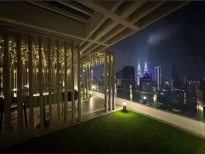 Een balkon met uitzicht op een verlichte stad.