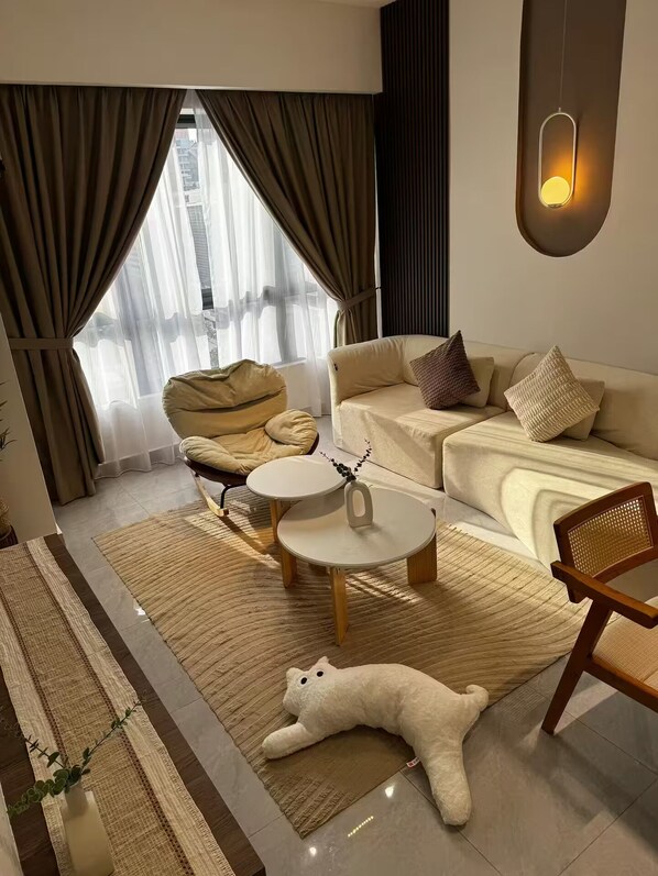 Een moderne woonkamer met een bank, fauteuil, rond bijzettafeltje en een decoratieve stoel.