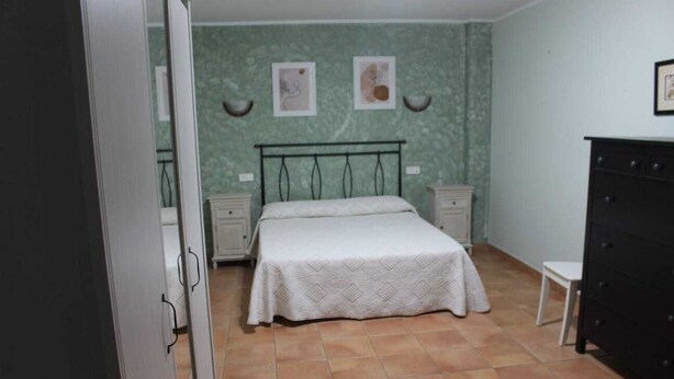 A bedroom with a bed, two bedside tables, a dresser, and a small stool. - House for 16 next to Burgo de Osma.  Hiking, wine, castles. Pets (Alcubilla del Marqués)