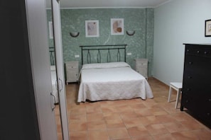 A bedroom with a bed, two bedside tables, a dresser, and a small stool.
