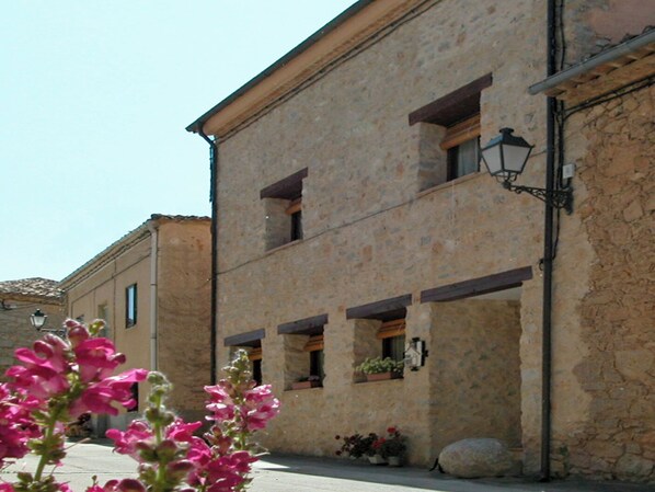 A stone building with multiple windows, a visible balcony, and a street lamp.