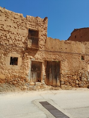 Un edificio rustico con un balcone, una piccola finestra e una porta.