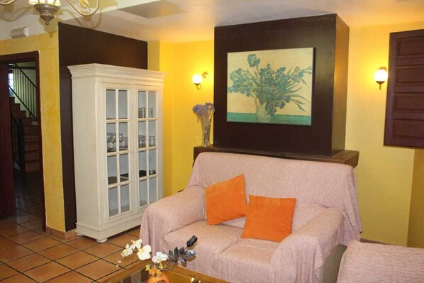 A living room with a sofa, a cabinet, a painting, and a staircase. - House for 16 next to Burgo de Osma. Hiking, wine, castles. Pets (Alcubilla del Marqués)
