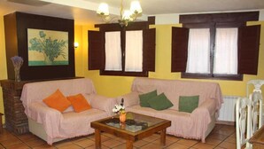 A living room with a sofa, a coffee table, a painting, and a window with shutters. - House for 16 next to Burgo de Osma.  Hiking, wine, castles. Pets (Alcubilla del Marqués)