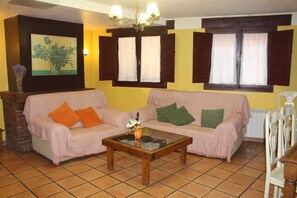 A living room with a sofa, a coffee table, a painting, and a window with shutters.