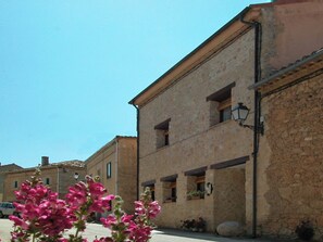 A stone building with a flat roof, multiple windows, and a street in front. - House for 16 next to Burgo de Osma. Hiking, wine, castles. Pets (Alcubilla del Marqués)
