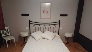 A neatly arranged bedroom with a bed, two bedside tables, a chair, and a wall-mounted picture. - House for 16 next to Burgo de Osma.  Hiking, wine, castles. Pets (Alcubilla del Marqués)