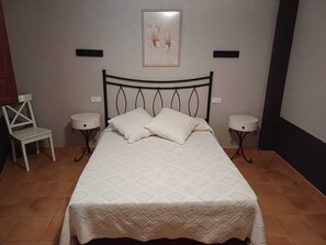 Una camera da letto ordinata con un letto, due comodini, una sedia e un quadro appeso al muro.