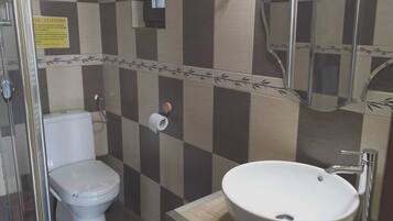 A bathroom with a toilet, sink, and shower.