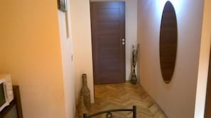 A hallway with a wooden door, a chair, and a vase. - Mozart Studios (Cluj-Napoca)