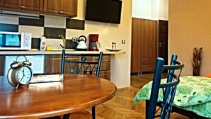 Una cocina con armarios de madera, microondas, cafetera y televisor en la pared.