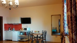 Un espacio habitable compacto con kitchenette, zona de comedor y un espejo grande.
