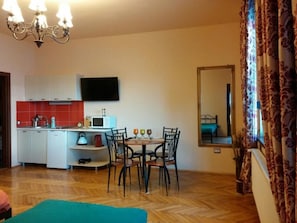 A compact living space with a kitchenette, a dining area, and a large mirror. - Mozart Studios (Cluj-Napoca)