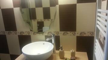 Une salle de bain avec un lavabo blanc, un miroir et un porte-serviettes.