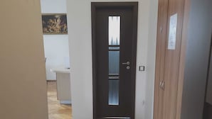 Un pasillo con piso de madera, una puerta oscura y un armario de madera con cerradura.