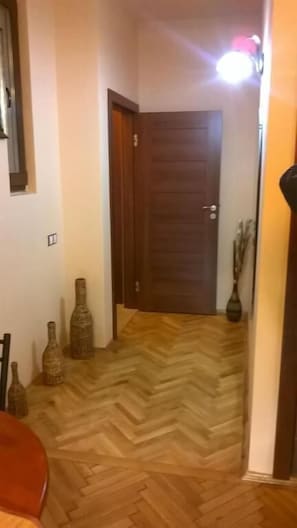 A hallway with a wooden floor, a closed door, and decorative vases. - Mozart Studios (Cluj-Napoca)