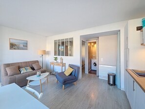 A compact living space with a sofa, armchair, small table, and a view of a washing machine in the background. - Apartment T2 BARCARÈS (Le Barcarès)