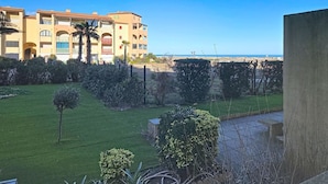 Un edificio residencial con varios balcones, un césped cuidado y una vista despejada del mar.