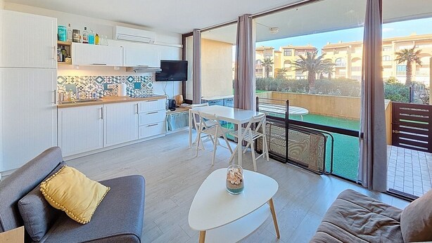Un apartamento moderno con cocina, comedor y balcón con vistas a edificios.