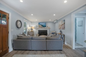 A living room with a sectional sofa, a fireplace, a clock, and a television.