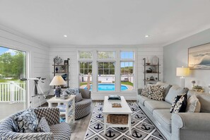 A spacious living room with a large window, a pool view, and a cozy seating area.