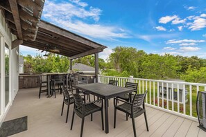 An outdoor patio with a table and chairs, a pergola, and a view of the surrounding greenery.