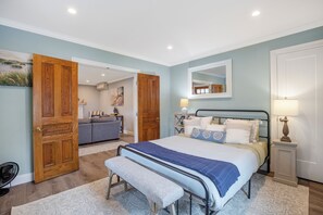 Quarto com cama, um banco, mesa de cabeceira e um espelho na parede.