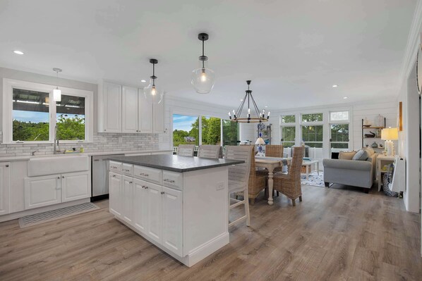 A spacious kitchen with white cabinetry, a central island, and pendant lighting.