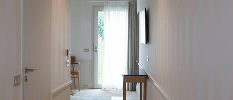 A hallway with a door, a small table, and a television mounted on the wall.