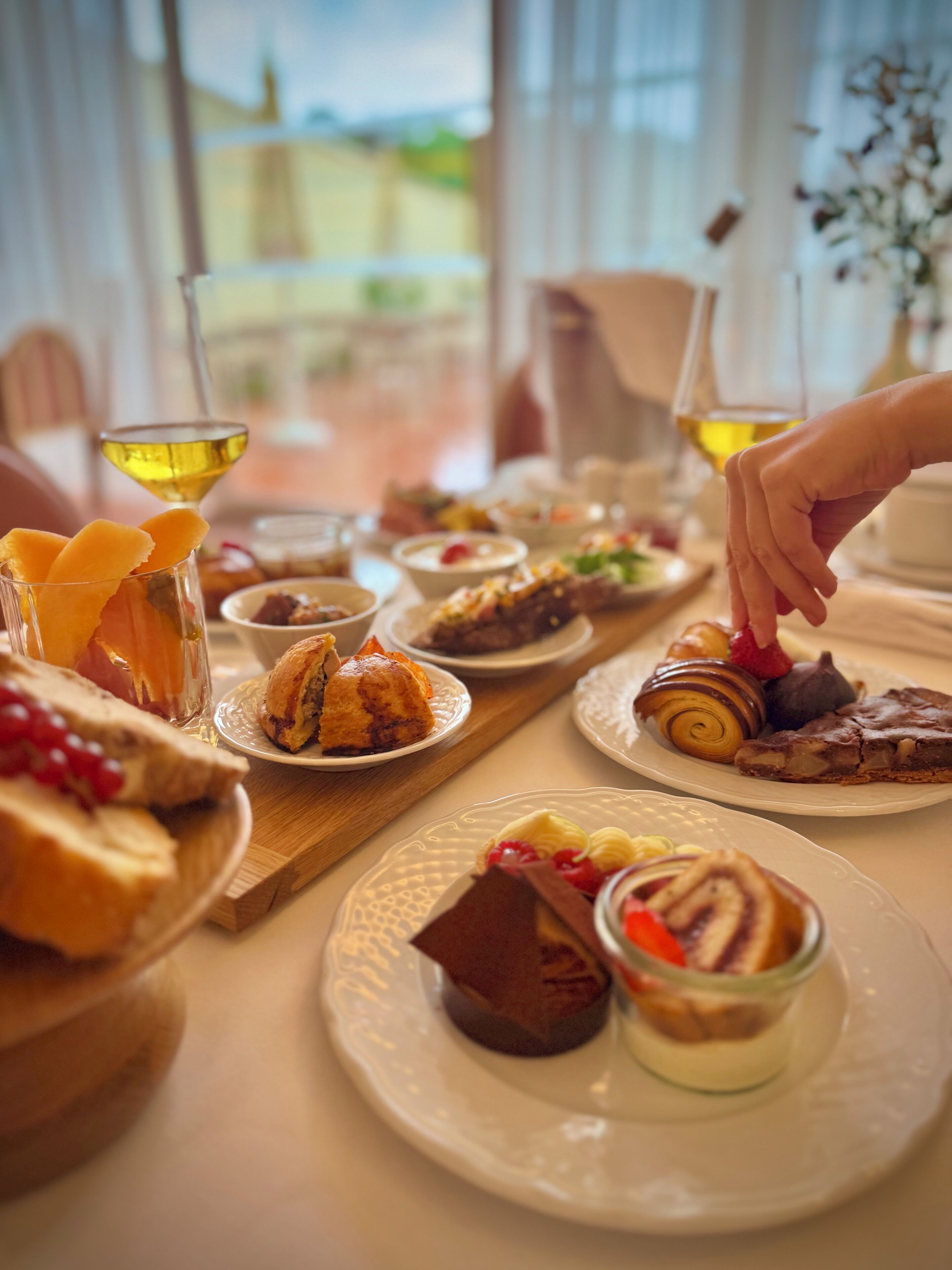 A table with various desserts and a glass of wine.