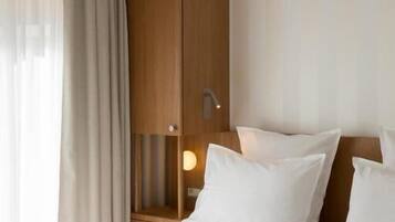 Une chambre d’hôtel avec un lit, une armoire en bois, une table de chevet et une lampe.