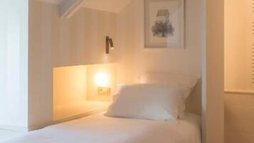 Un dormitorio con cama, una lámpara de pared, un cuadro enmarcado y suelo a cuadros.