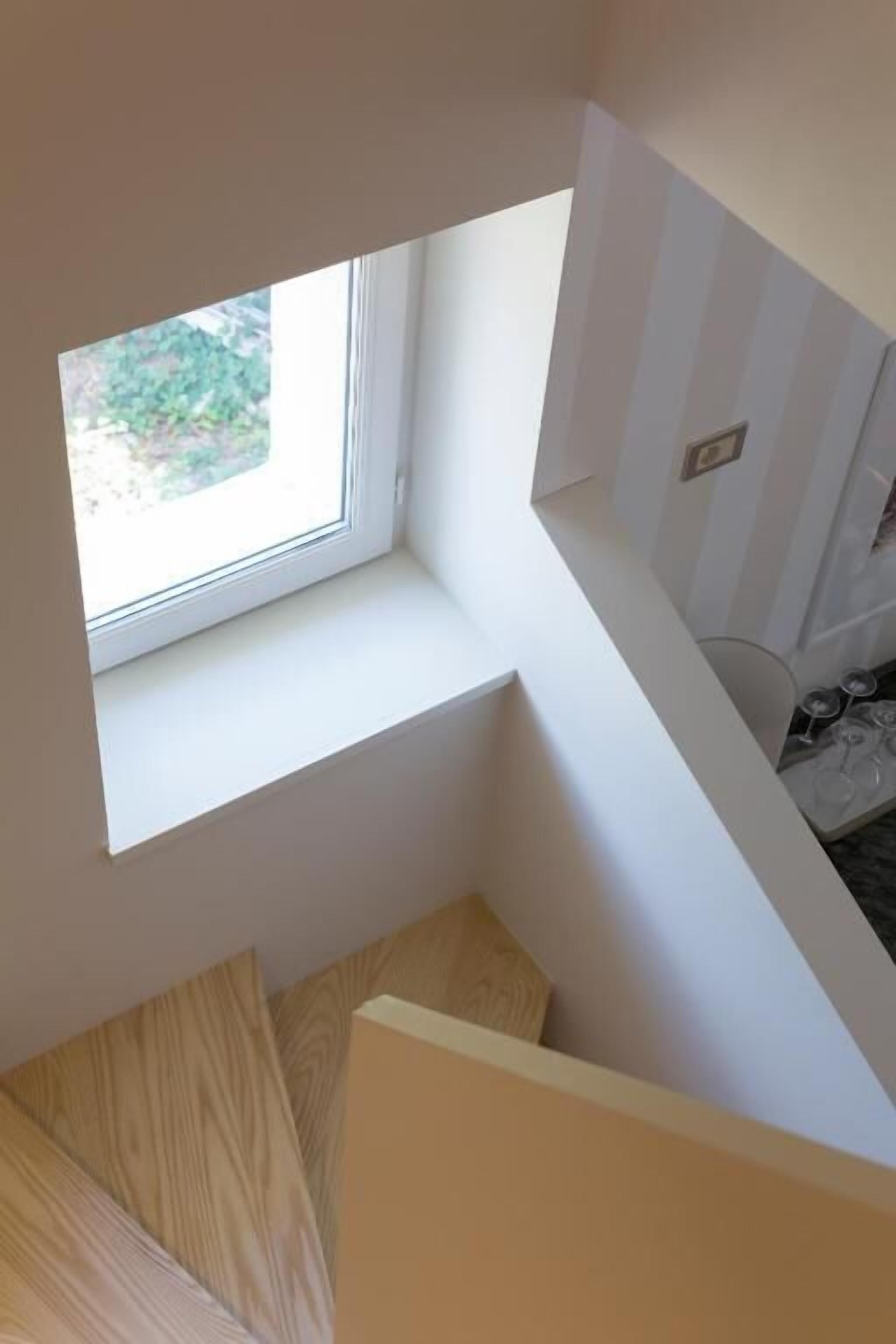 A corner of a room with a window, a white wall, and a door.
